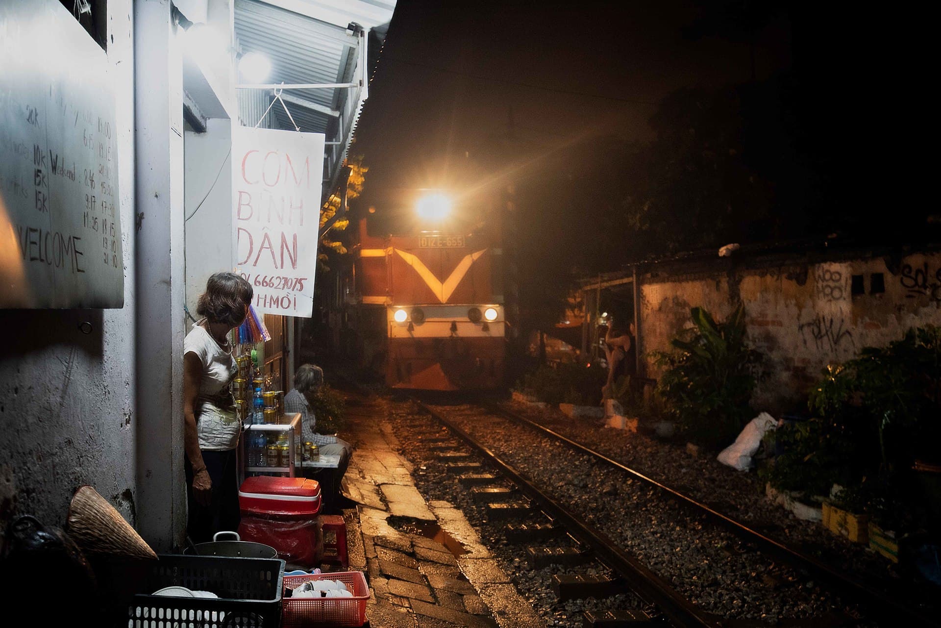 A train passing inches from cafes and food vendors on Train Street in Hanoi's Old Quarter at night — the city's signature long-weekend image